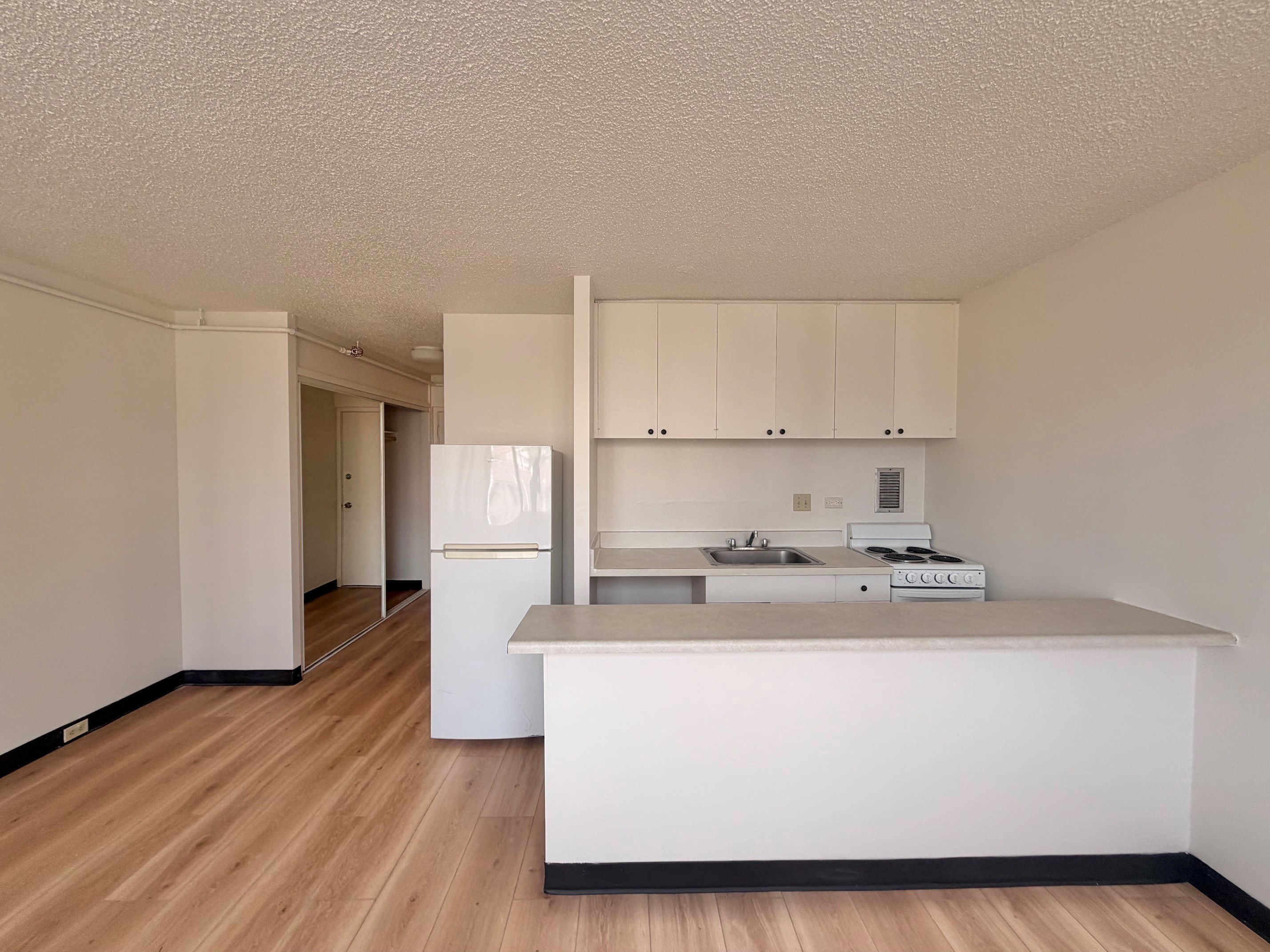 A kitchen with white cabinets and a wooden floor.